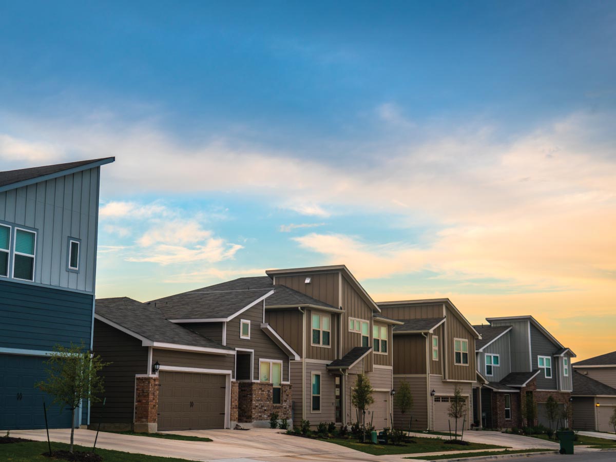 Row of new homes on a street at sunset.