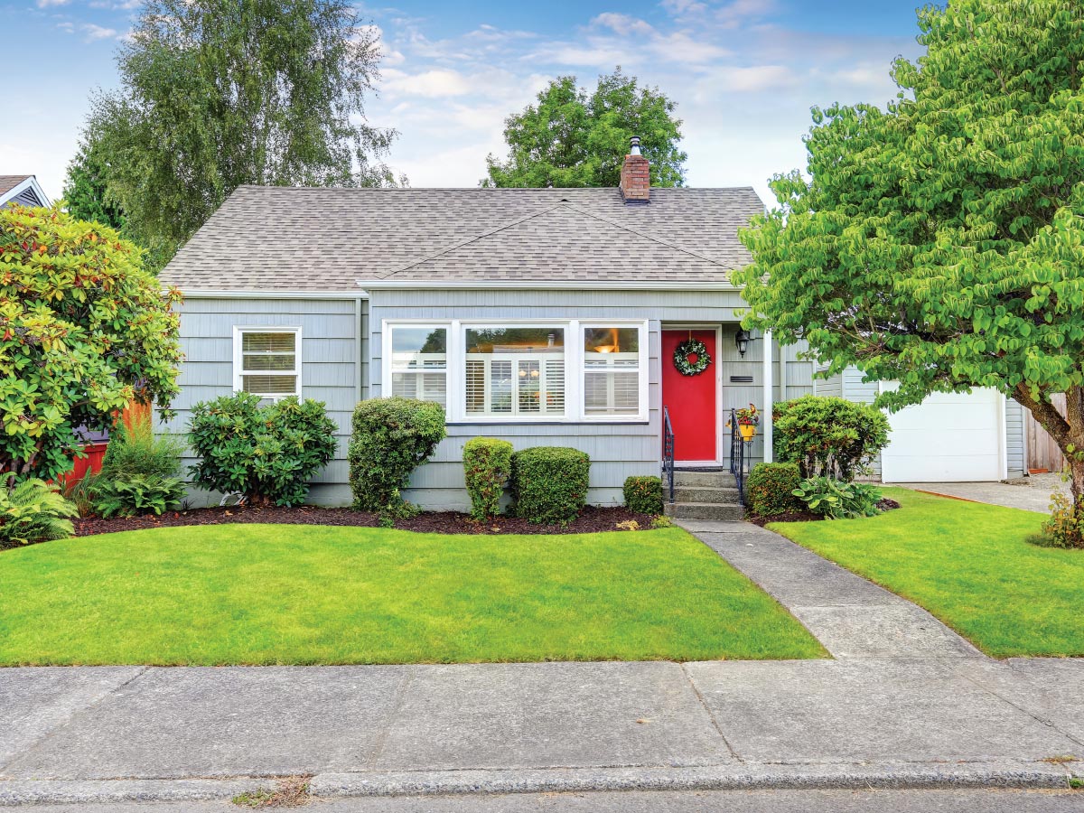 A small rental home with a red door on a quiet street.